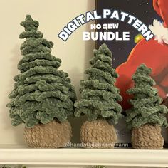 three knitted christmas trees sitting on top of a mantle in front of a poster