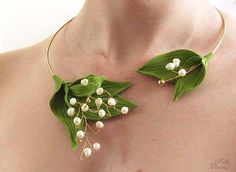 a close up of a person wearing a necklace with flowers and leaves attached to it