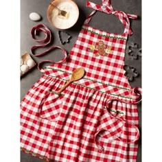 a red and white checkered apron with gingerbreads on it next to baking utensils