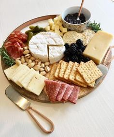 a platter with cheese, crackers, grapes, nuts and meats on it