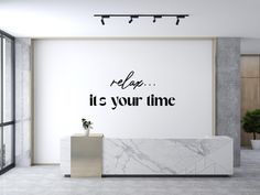 an office lobby with a marble counter and large wall decal that says relax it's your time