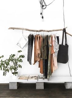 a white bench topped with lots of clothes next to a plant and sign that says live yourstyle