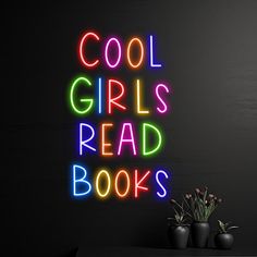 a neon sign that says cool girls read books next to some potted plants on a table