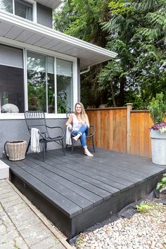 two black chairs sitting on top of a wooden deck next to a building and trees