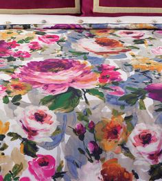 an image of a bed with flowers on the comforter and pillow cases in different colors