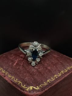 an antique diamond and blue sapphire ring on top of a red velvet book with gold trimming