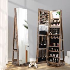 a mirror sitting next to a tall wooden shelf filled with bottles and other items on top of a hard wood floor