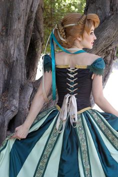 a woman in a green and white dress sitting on a tree