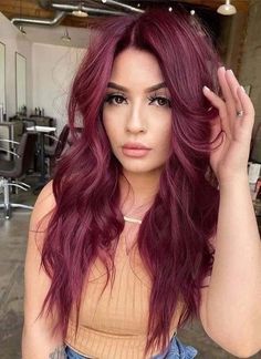 a woman with long red hair is posing for the camera in an open room and has her hand on her head