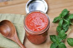 a wooden spoon sitting on top of a table next to a jar of tomato sauce