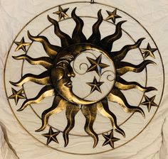 a metal sun and moon decoration hanging on a white sheet with stars in the background