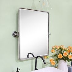 a bathroom sink sitting under a large mirror next to a vase with flowers in it