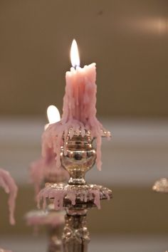 a candle that is sitting on top of a metal stand with pink icing around it