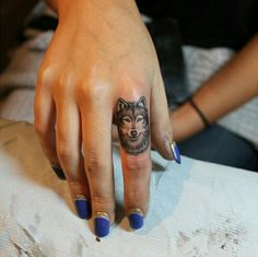 a woman's hand with a wolf tattoo on it