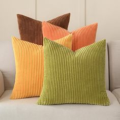 three pillows sitting on top of a white couch