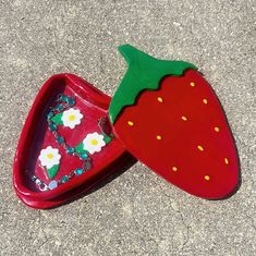 two plastic strawberries sitting on the ground next to each other with beaded decorations