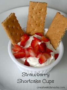 strawberry shortcake cups with whipped cream and crackers in a bowl on a white plate