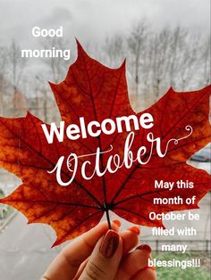 a person holding up a red leaf with the words welcome october