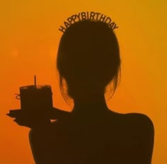 the silhouette of a woman holding a birthday cake in front of an orange sky with happy birthday written on it