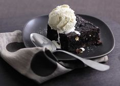 a piece of chocolate cake with ice cream on top is sitting on a black plate