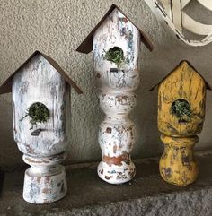 three painted birdhouses sitting next to each other on a ledge in front of a wall