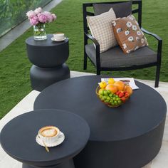 a black table with fruit on it in the middle of a lawn area next to two chairs