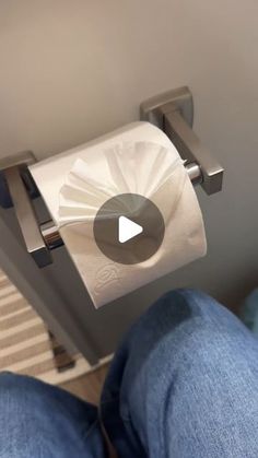 someone is sitting down with their feet on the toilet paper roll dispenser