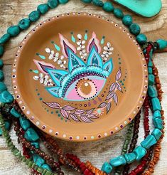 a bowl with beads and beaded necklaces around it on top of a wooden table