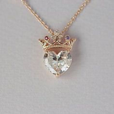 a heart shaped necklace with a crown on it's head and two diamonds in the middle