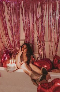 a woman sitting in a bathtub with a birthday cake