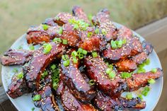 a plate full of barbecue ribs covered in sesame seeds and green onions