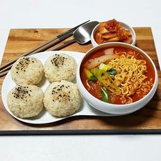 a wooden tray topped with rice and bowls filled with food next to chopsticks