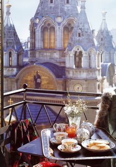 an outdoor table with food and drinks on it in front of a castle like building