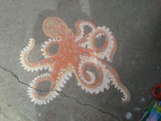 an orange and white octopus is on the ground next to some crayon markers