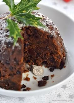 a piece of chocolate cake with mint sprig on top in a white bowl