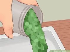 a person pouring something into a container with green stuff in it on top of a wooden table