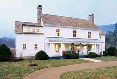 a large white house sitting on top of a lush green field