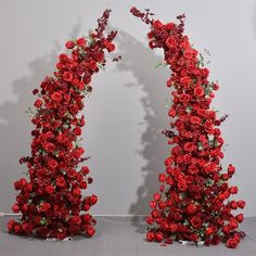 two red roses are arranged in the shape of an arch with leaves and flowers on it