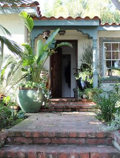 a house that has some plants in front of it and stairs leading up to the door