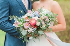 the bride and groom are posing together for a wedding photo with flowers in their bouquet