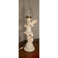 a white lamp with an angel figurine next to it on a wooden table