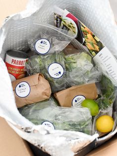 a cardboard box filled with lots of different types of vegetables and fruit in it's wrapper