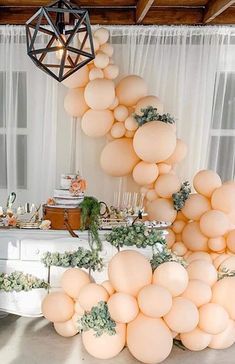 a table topped with lots of balloons next to a white dresser covered in greenery