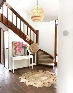 an entryway with stairs and rugs on the floor next to a white table