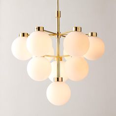 a chandelier with six white globes hanging from it's brass frame