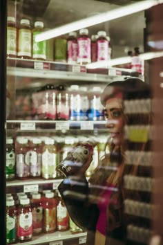 a woman holding a bottle in front of a store window