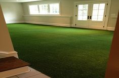 an empty room with green carpet and white trim on the door way to another room