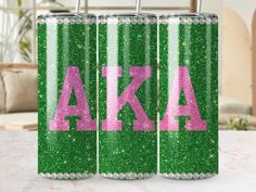 two green canisters with pink letters on them sitting on top of a table