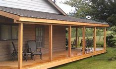 a wooden house with chairs on the front porch and covered in wood shinnings