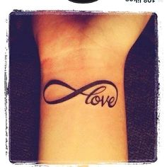 a wrist tattoo with the word love written in cursive writing and an infinite symbol